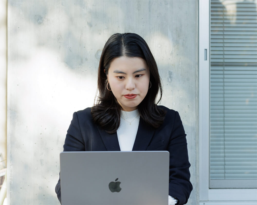 白衣を着用し、製造・開発現場で真剣な表情で作業に取り組む若手社員