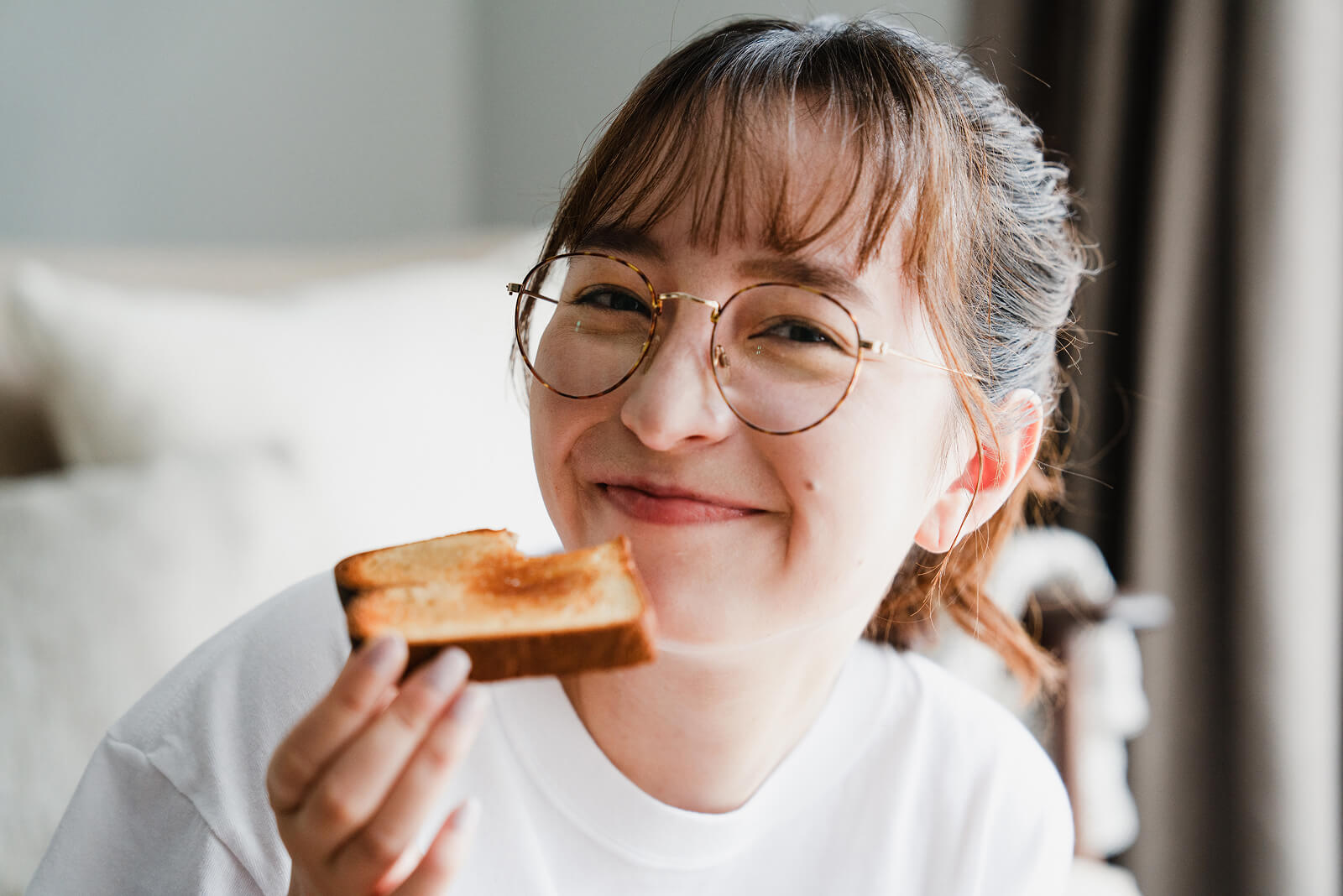 焼き立てのトーストを手に笑顔を見せる女性